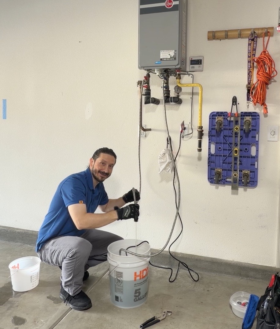 Dustin Swad of Ultra Home Repair flushing a Rheem tankless water heater with hoses and a circulation bucket